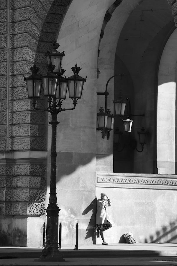 photographie noir et blanc au Louvre à  Paris, une femme entre l'ombre et le soleil